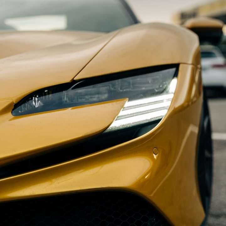 Close-up of a yellow sports car's front headlight and sleek design.