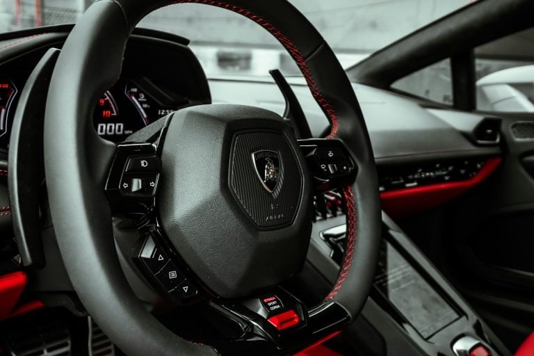 Close-up of a modern car steering wheel with a sporty design and red accents.
