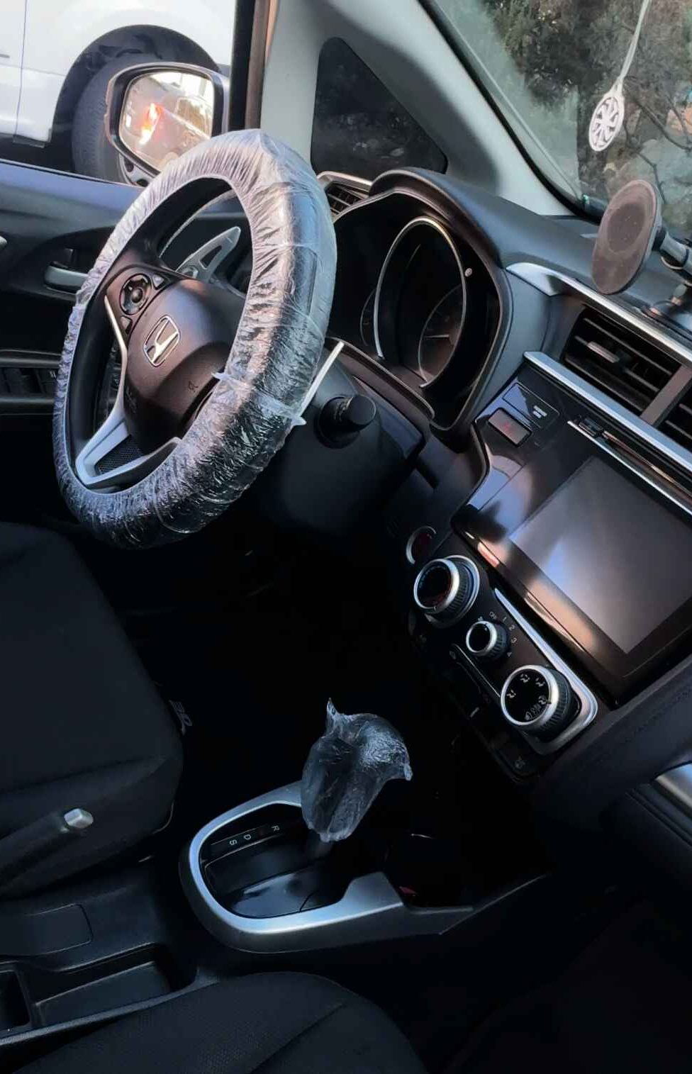 Interior view of a car with a steering wheel, gear shifter, and dashboard controls.